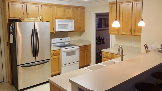 A modern kitchen with wooden cabinets, stainless steel appliances, a microwave, and pendant lighting.