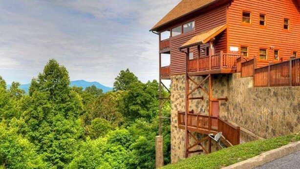 Un edificio de madera roja con base de piedra, un balcón y una escalera.