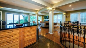 A spacious kitchen with a large island, wooden cabinets, and a dining area with a round table and chairs. - 2024 remodeled historic Lake Michigan waterfront Union Pier home with spa. (Chikaming Township)