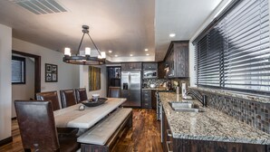 A modern kitchen with a granite countertop, stainless steel appliances, and a dining area with a bench and chairs. - Luxurious and modern townhome with a ton of room! (Park City)