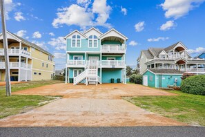 Stunning coastal home with a front porch, balcony, and well-manicured lawn.