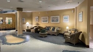 A lobby with a seating area featuring sofas and armchairs, a patterned carpet, and framed artwork on the walls. - Ocean front w/Balcony -the "How Sweet It Is!" condo with breathtaking Views (Daytona Beach)