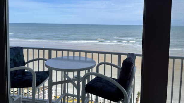 A balcony with a view of the ocean. There are two chairs and a small table. - Ocean front w/Balcony -the "How Sweet It Is!" condo with breathtaking Views (Daytona Beach)