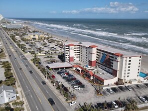 Un hôtel situé sur la côte, avec plusieurs étages, un parking et une vue sur la plage et l’océan.