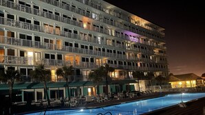 A multi-story hotel with balconies, a swimming pool, and outdoor seating. - Ocean front w/Balcony -the "How Sweet It Is!" condo with breathtaking Views (Daytona Beach)