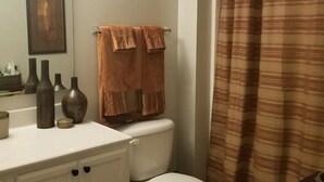 Ein Badezimmer mit einem weißen Waschbecken, zwei Handtüchern und einer Toilette.