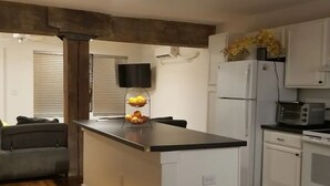 Eine kompakte Küche mit Kochinsel, weißen Schränken, einer Mikrowelle und einem Kühlschrank.