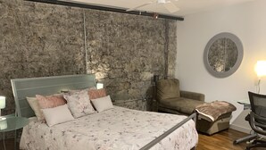 Ein Schlafzimmer mit einem großen Bett, einer Couch, einem Sessel und einem runden Spiegel an der Wand.