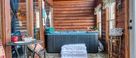 L’intérieur chaleureux d’un chalet en rondins, avec un décor en bois, une petite table ronde entourée de chaises, un pouf blanc et moelleux, et un bain à remous.