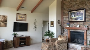 A living room with a fireplace, a television, and a ceiling fan.