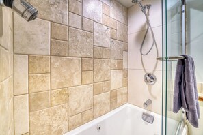 A bathroom with beige tiles, a glass shower enclosure, and a white bathtub. - Charming & upscale Condo in the Heart of Aspen (Aspen)