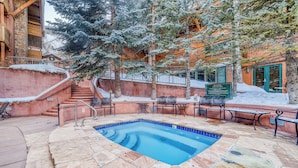 A stone pool with a blue border, surrounded by stone steps and metal railings. - Upscale & Charming Condo  (Aspen)