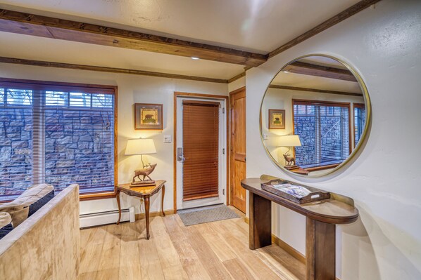 A hotel entrance with a wooden bench, a small table with a lamp, a mirror, and a door with a wooden frame. - Charming & upscale Condo in the Heart of Aspen (Aspen)