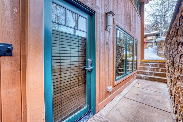 A wooden building with a green door, a window, and a stone wall.