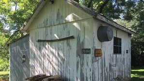 A rustic wooden shed with a weathered exterior, a small window, and a door.