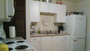 A kitchen with white cabinets, a stove, a sink, and a refrigerator.