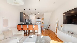 A modern living room with a sofa, a coffee table, and a kitchen area in the background. - Walk to Stadium + GWCC | Modern 2BR w Parking (Atlanta)