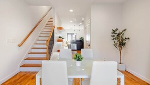 A modern interior with a staircase, dining area, and kitchen. - Walk to Stadium + GWCC | Modern 2BR w Parking (Atlanta)