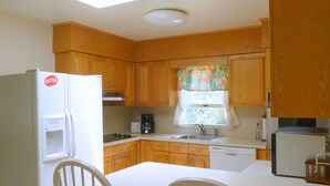 A compact kitchen with wooden cabinets, a white refrigerator, a coffee maker, and a dishwasher.