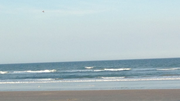 Ein Strand mit Wellen und blauem Himmel.