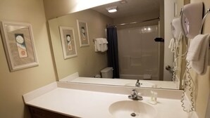 Un baño con lavamanos blanco, espejo y ducha.