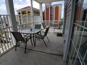 A balcony with a table and chairs, a view of buildings, and a gated entrance. - MBV 4Br/3Ba - 301B (Myrtle Beach)