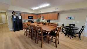 Una cocina con armarios de madera, un refrigerador negro, un microondas y una mesa de comedor con sillas.