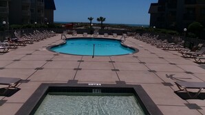 A swimming pool with lounge chairs and a view of the beach.
