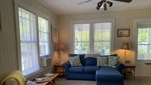 A cozy living room with a blue sofa, a wooden chair, and a small table with a lamp.