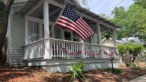 A house with a porch, an American flag, and a string of pink and white flags.