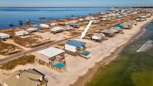Oversigtsbillede af et kystområde med strandhuse, en vej og en mole, der strækker sig ud i vandet.