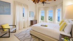 A bedroom with a large bed, a desk, a chair, and a view of the landscape. - Gardenia Newly Renovated with Tesla Power Walls! (St. John)