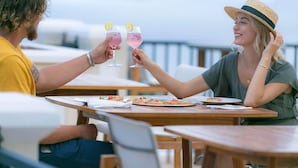 A couple toasting with drinks at an outdoor table with a view of the sea. - Gardenia Newly Renovated with Tesla Power Walls! (St. John)