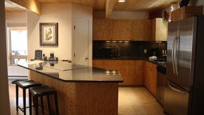 A modern kitchen with wooden cabinets, a stainless steel refrigerator, and a granite countertop. - Beautiful Mountain Retreat Just Minutes From the Slopes!! (Taos Ski Valley)