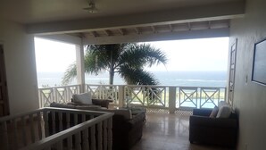 A balcony with a view of the ocean, furnished with a sofa and chairs, and a railing. - Spacious Indoor/Outdoor living. Private pool. Amazing ocean views (Half Moon Bay)