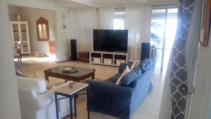 A living room with a TV, sofa, and coffee table. - Spacious Indoor/Outdoor living. Private pool. Amazing ocean views (Half Moon Bay)