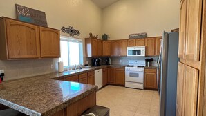 A kitchen with wooden cabinets, granite countertops, a stainless steel refrigerator, and a built-in oven.