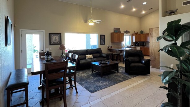 A spacious living area with a dining table, sofa, and a kitchen in the background.