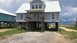 Een huis met twee verdiepingen, een balkon, een houten terras en uitzicht op de oceaan.