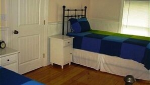 A bedroom with a bed, a bedside table, a nightstand, a window, and a door.