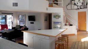 Eine moderne Wohnung mit Küche, Essbereich und Wohnzimmer. Eine Treppe verbindet die beiden Etagen.