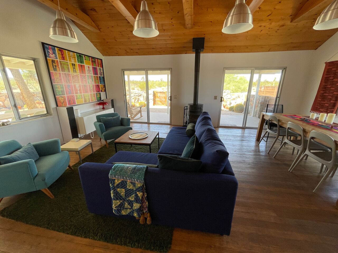 A spacious living area with a large sofa, a coffee table, and a fireplace. There are two doors leading to a patio area.