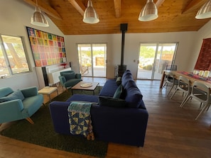A spacious living area with a large sofa, a coffee table, and a fireplace. There are two doors leading to a patio area.