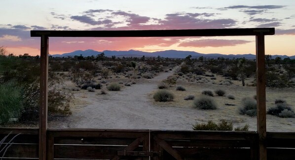 A desert landscape with a dirt path leading towards mountains, viewed through a wooden frame. - Secluded 20 Acre Retreat with Guest House and Pool/Spa (Joshua Tree)