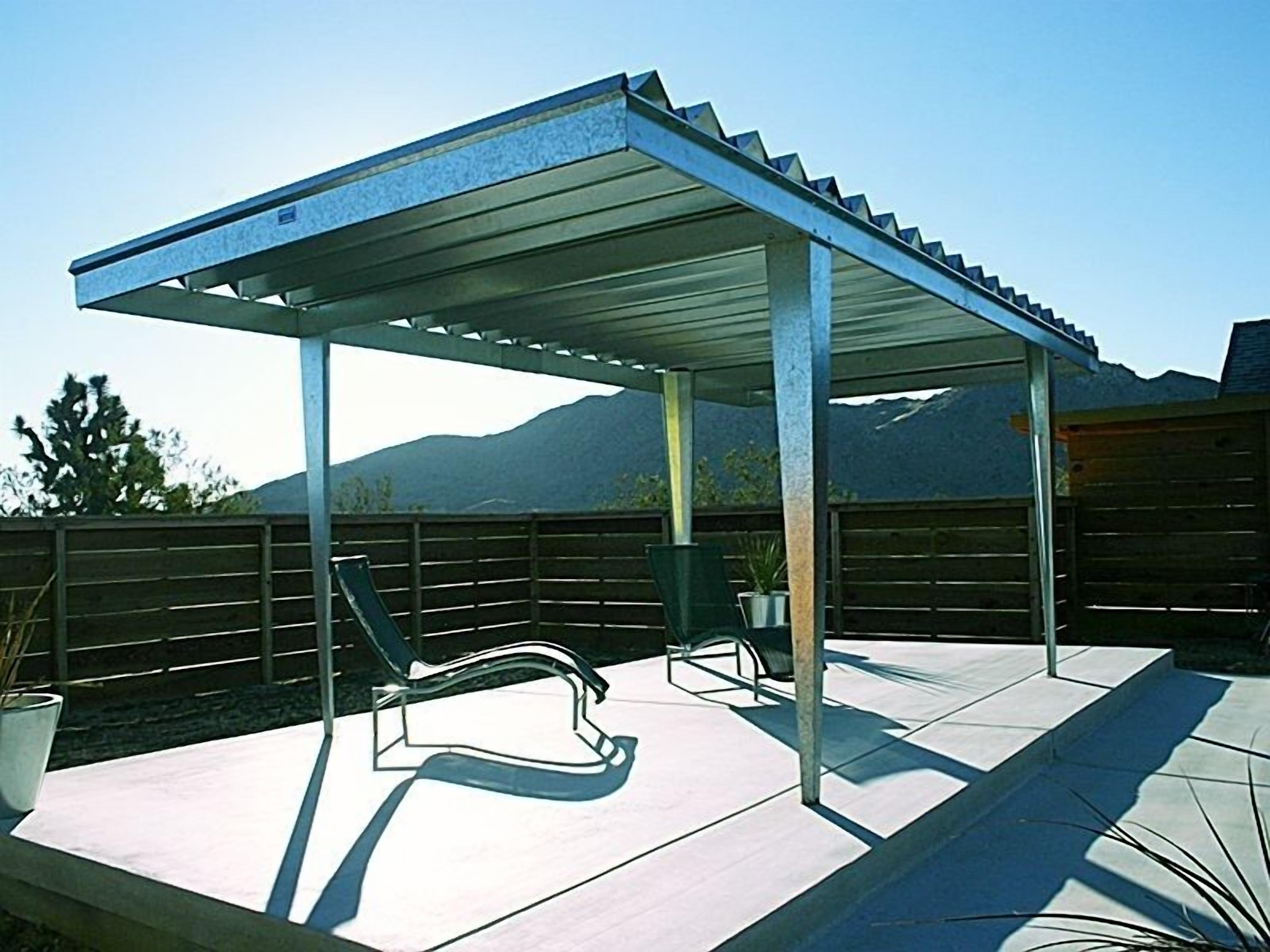 A covered patio area with two lounge chairs and a potted plant.