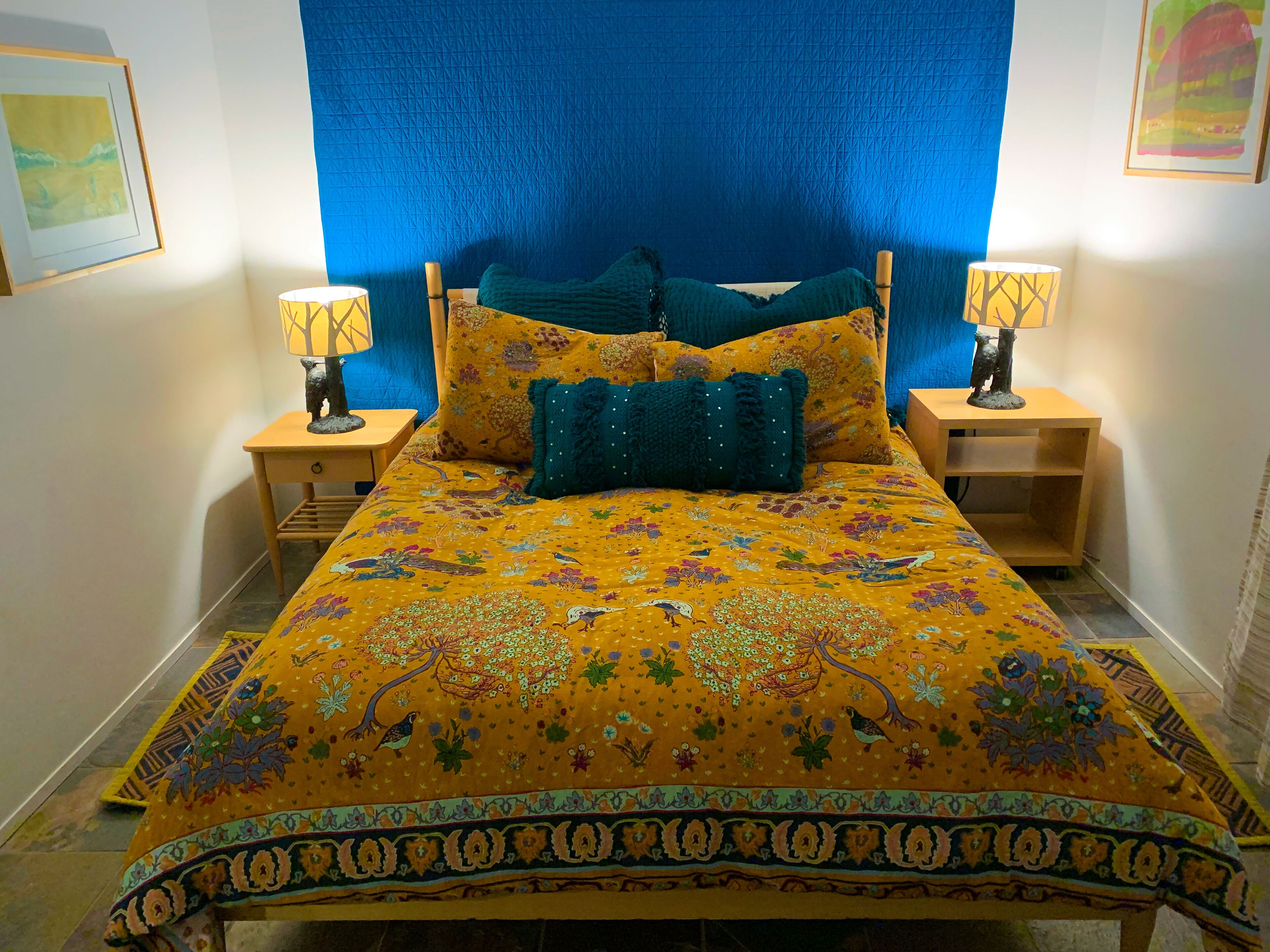 A bed with a floral bedspread, two nightstands, and a blue headboard.