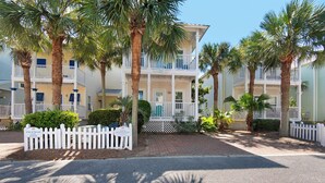 A beachfront hotel with multiple balconies, palm trees, and a white picket fence. - Breakaway~South of 30A~Short walk to the beach, Restaurants and More! (Santa Rosa Beach)