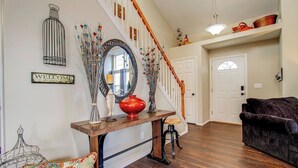 A staircase with a wooden handrail and white walls, leading to a door. - Spacious 4BR w/ EV Charger & Hot Tub (Colorado Springs)