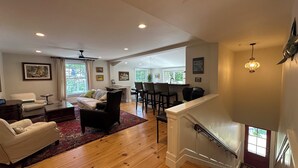 A spacious living room with a fireplace, a dining area, and a staircase leading to an upper level.