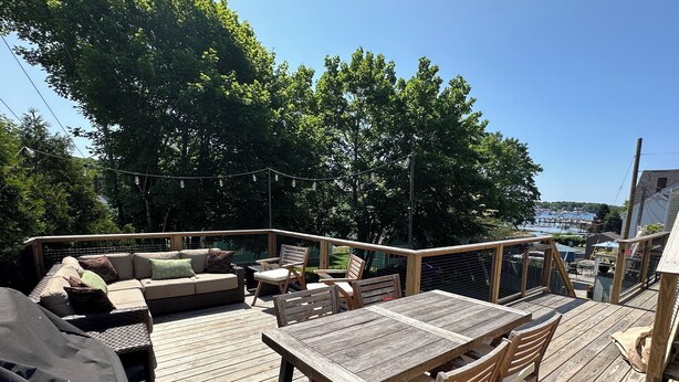 A wooden deck with a table and chairs, a sofa, and a covered grill area.